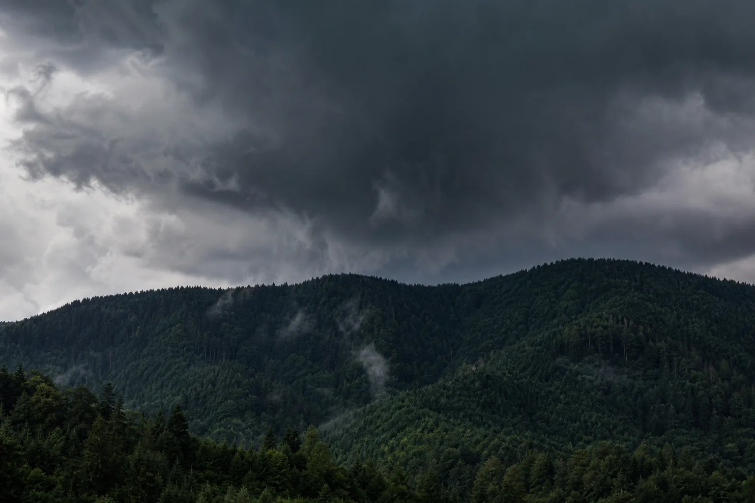 Dark storm clouds gathering low over a ridgeline